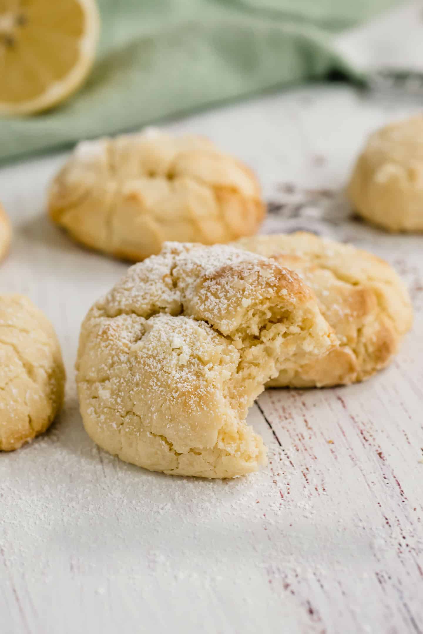 Bitten lemon crinkle cookie on a wooden board