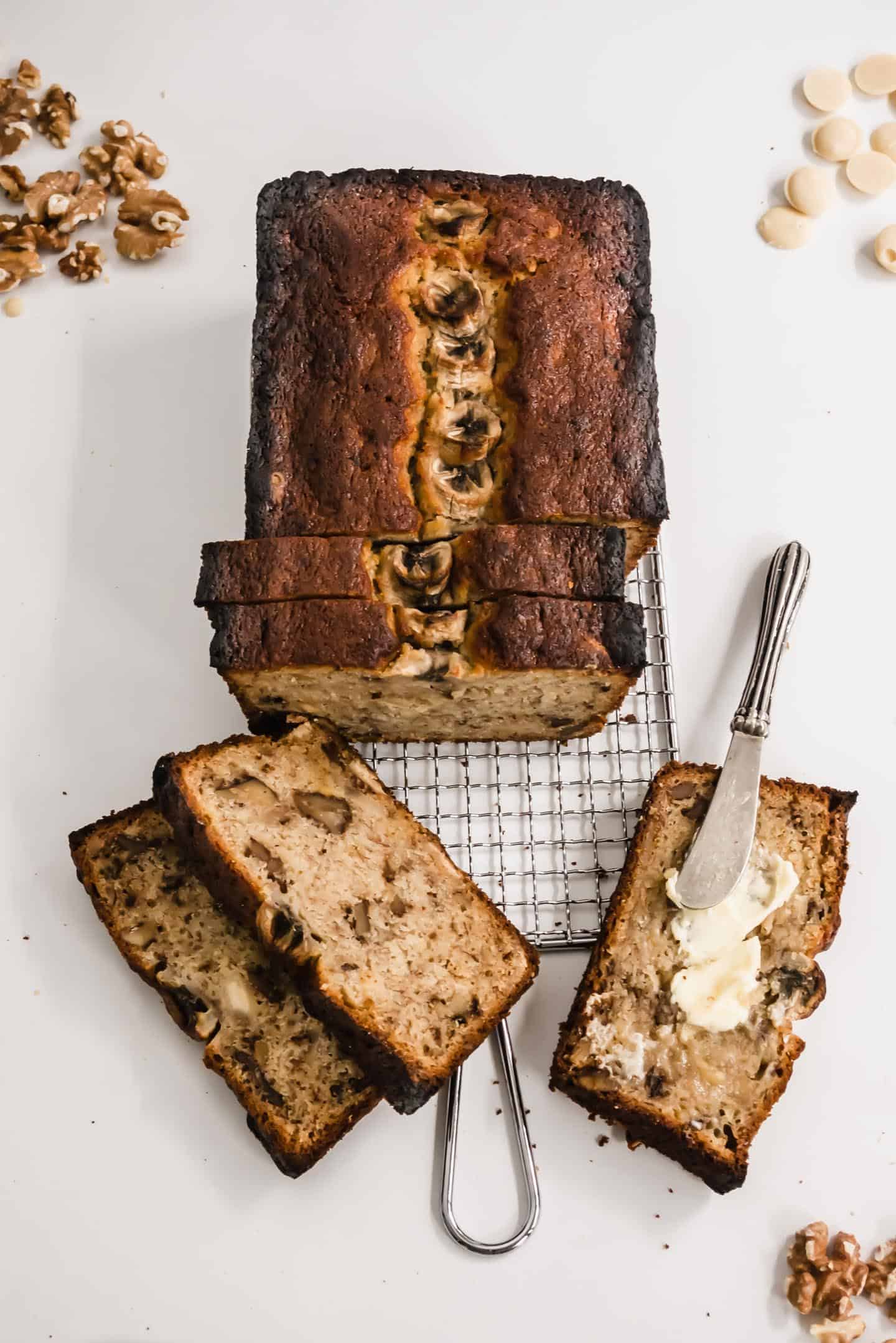 Banana bread on a colling rack, with some butter on one slice