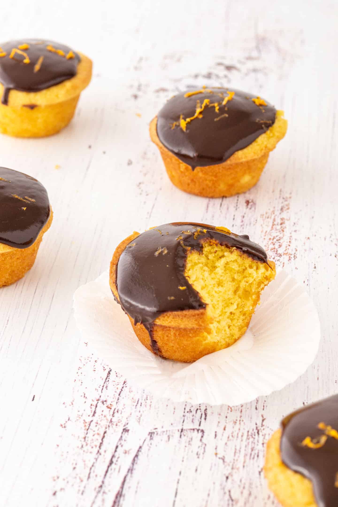 Close up of a bitten mandarin muffin and a little jug with dripping chocolate behind