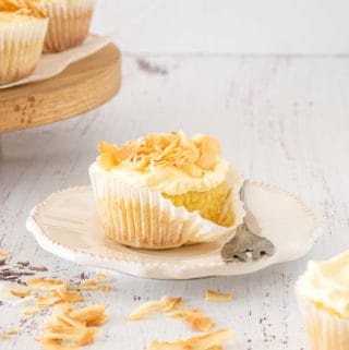 Coconut Tres Leches Cupcakes with a fork and a wooden stand at the background.