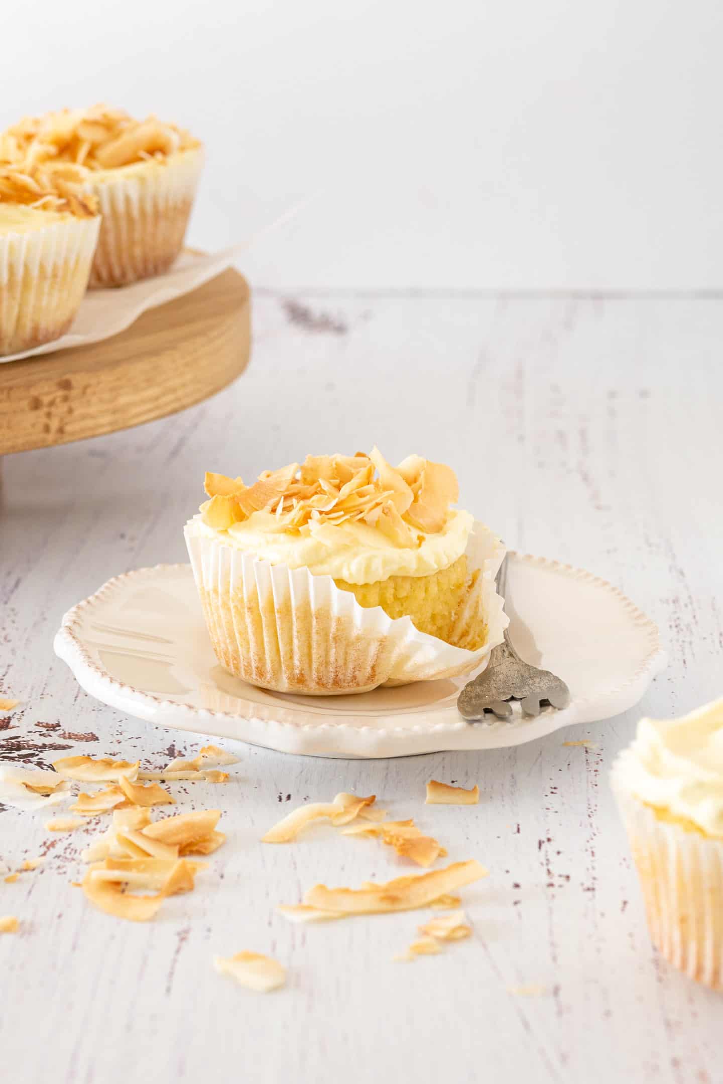 Coconut Tres Leches Cupcakes with a fork and a wooden stand at the background.