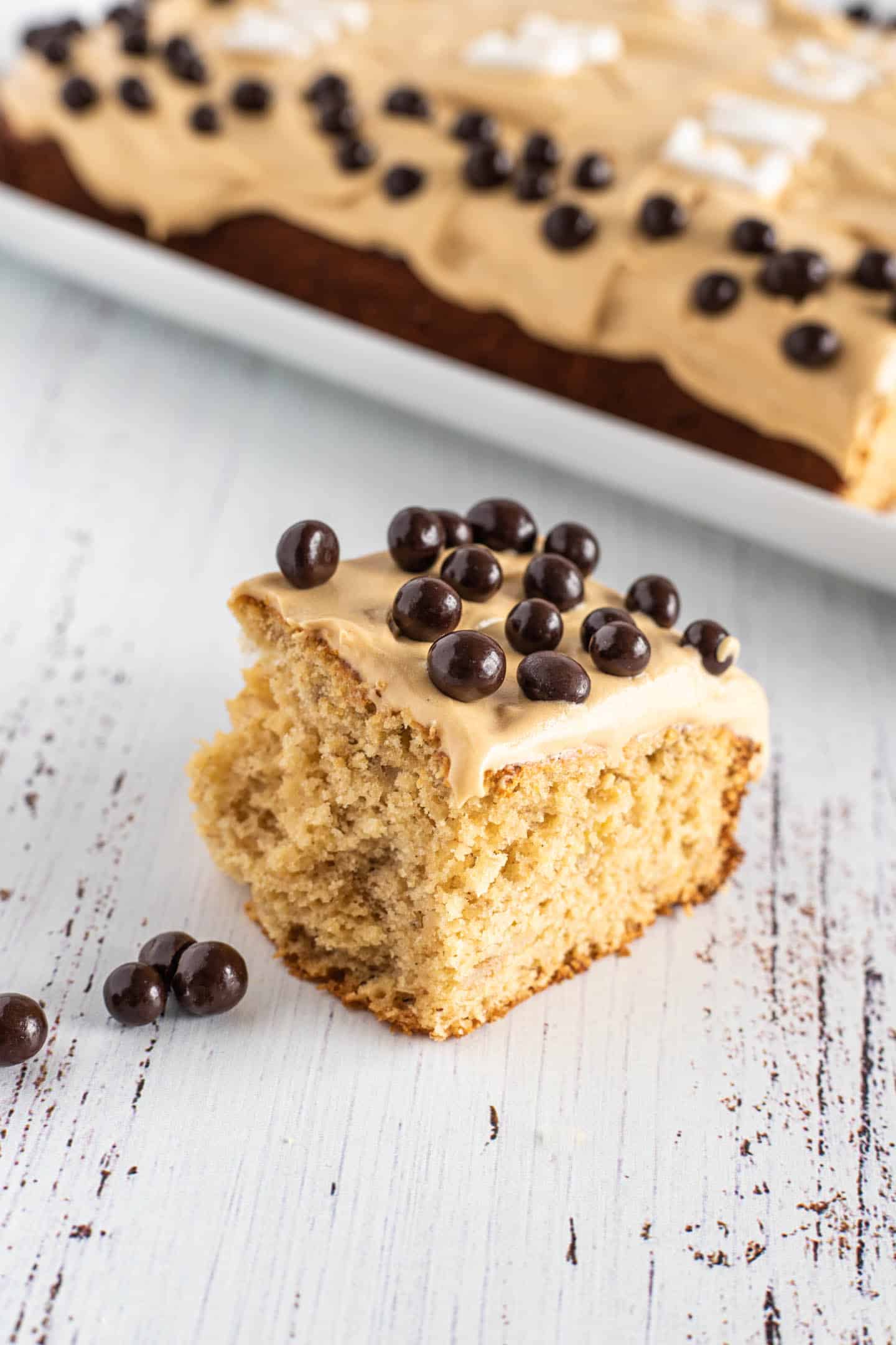 Slice of banana sheet cake with chocolate-covered blueberries