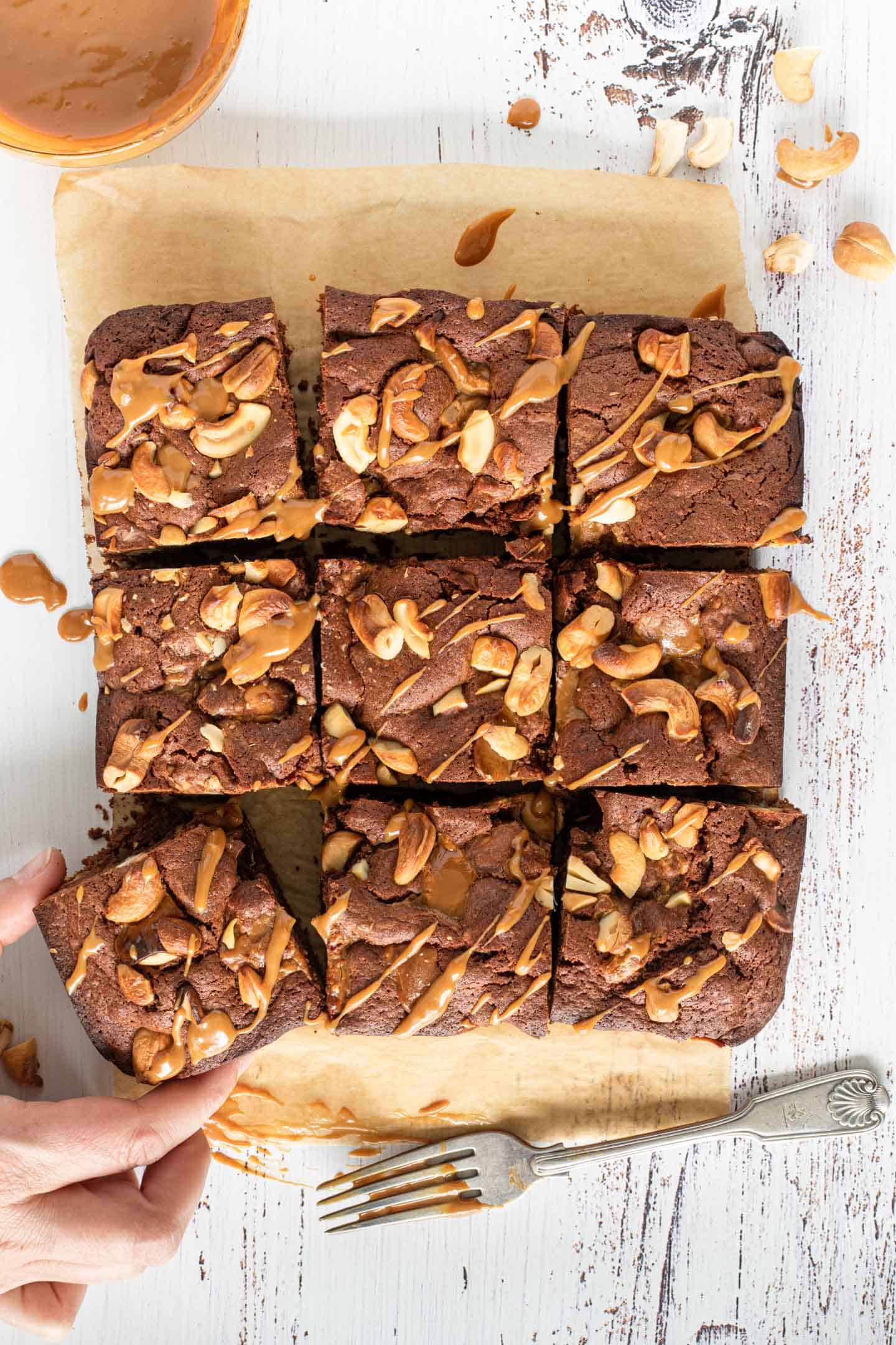 Brownies with cashews and dulce de leche cut into squares on brown parchment paper