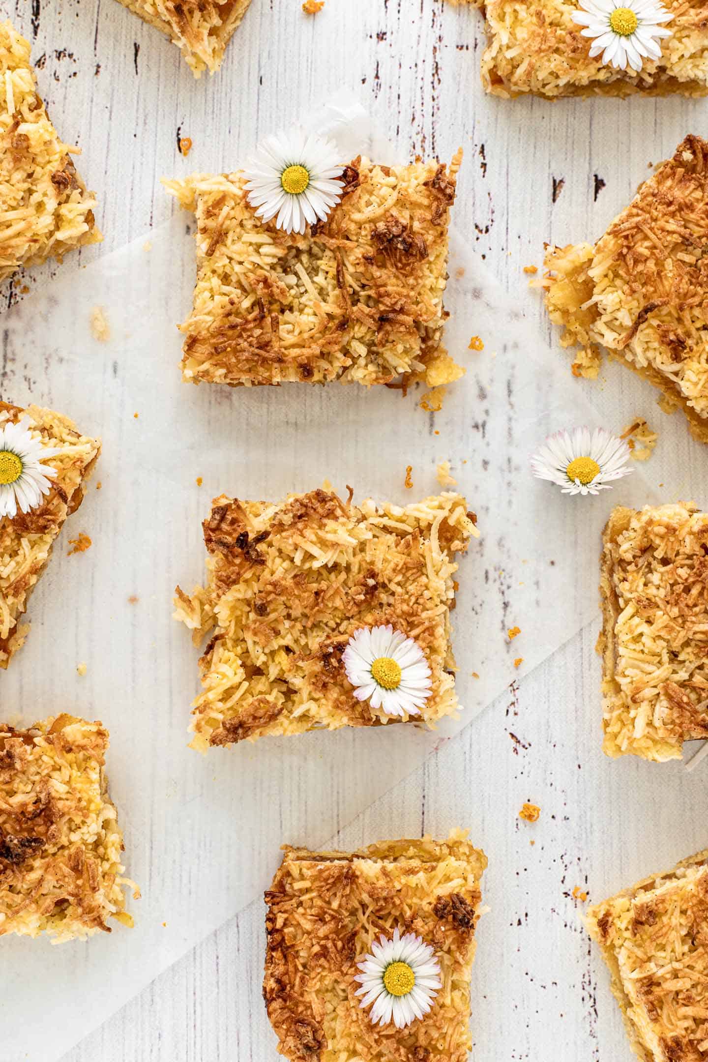 Overhead shot of square bars of coconut and orange marmalade tart with little daisies on top