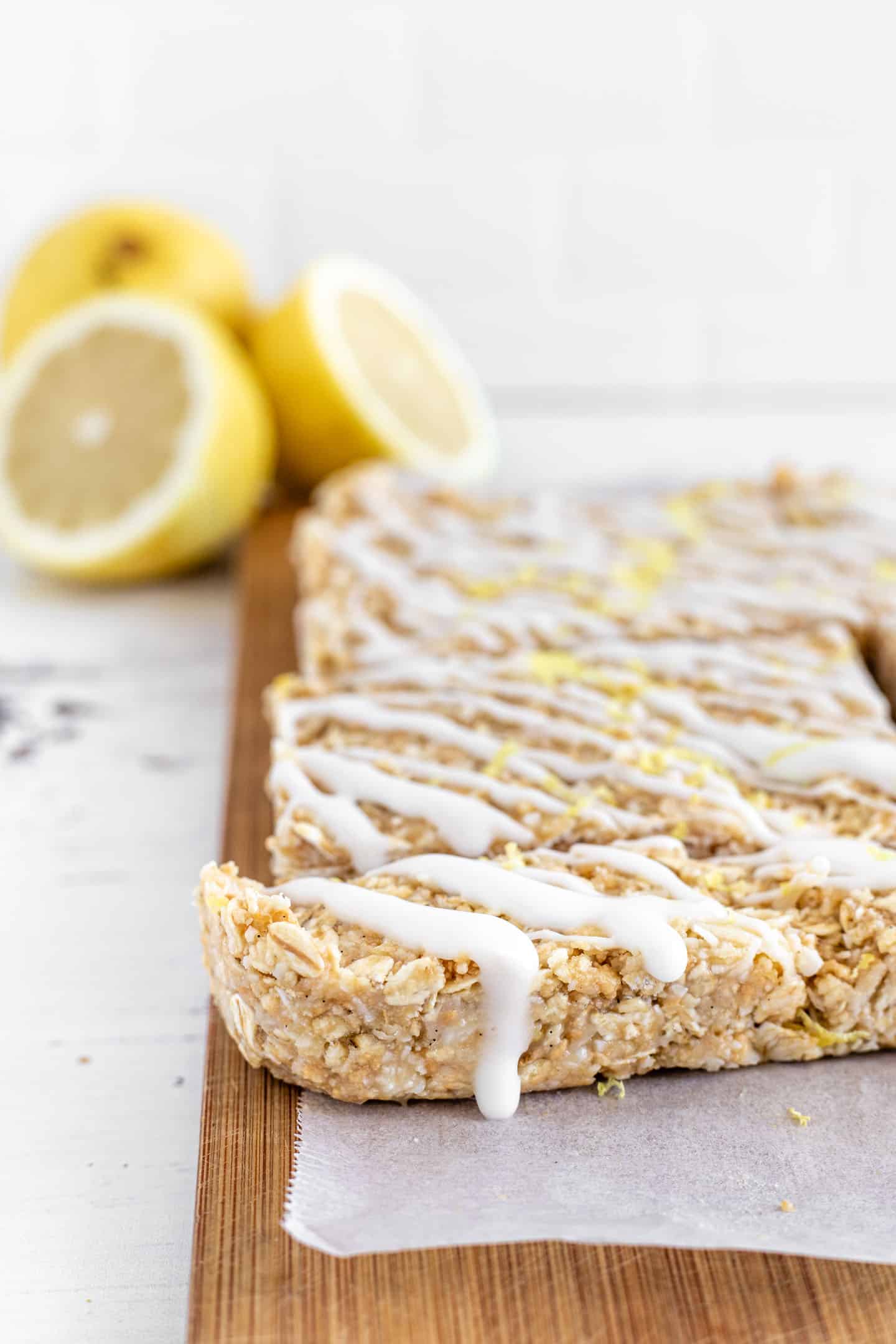 Lemon, coconut and oats bars on a wooden board and some lemons in the background