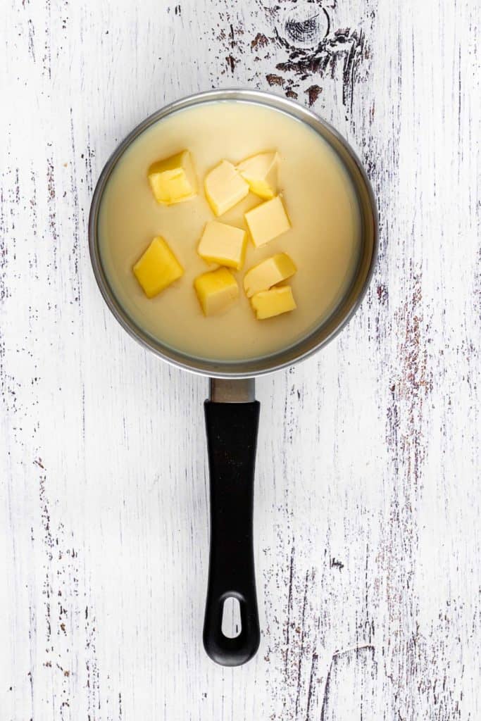 Olla pequeña con leche condensada y manteca cortada en cuadraditos