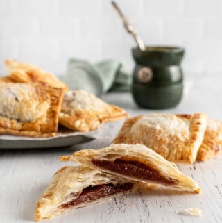 Empanadita de membrillo cortada al medio con un mate verde por detrás y un plato