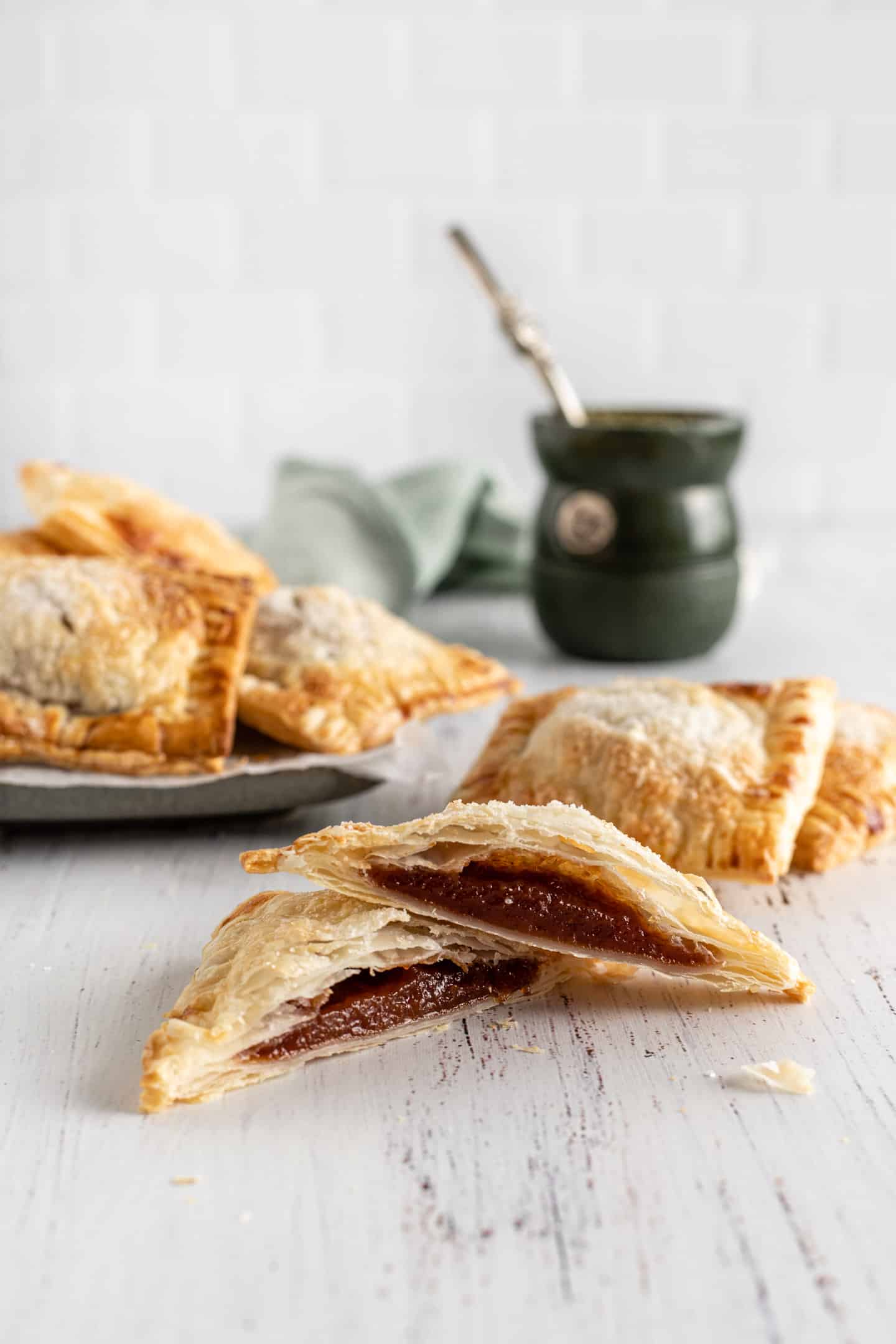 Empanadita de membrillo cortada al medio con un mate verde por detrás y un plato