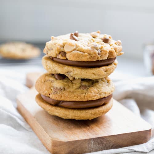 two chocolate chip cookies alfajores filled with dulce de leche on a wooden board