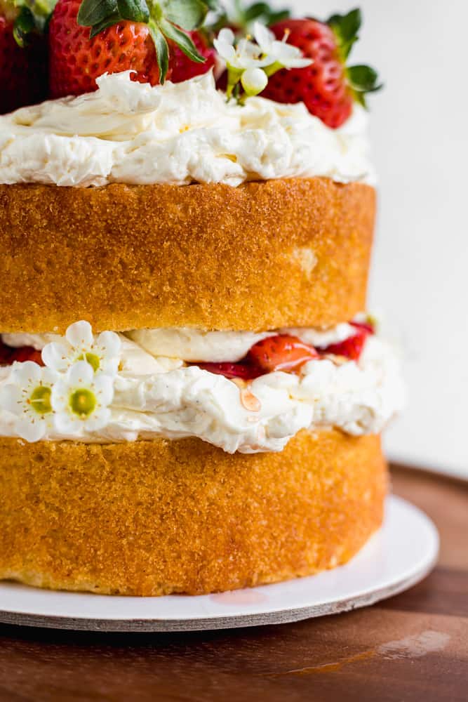 Close up of a naked layered cake filled with honey buttercream and fresh strawberries