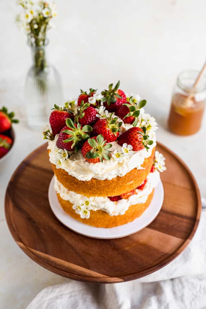 Overhead shot of a naked sponge cake on a wooden cake stand