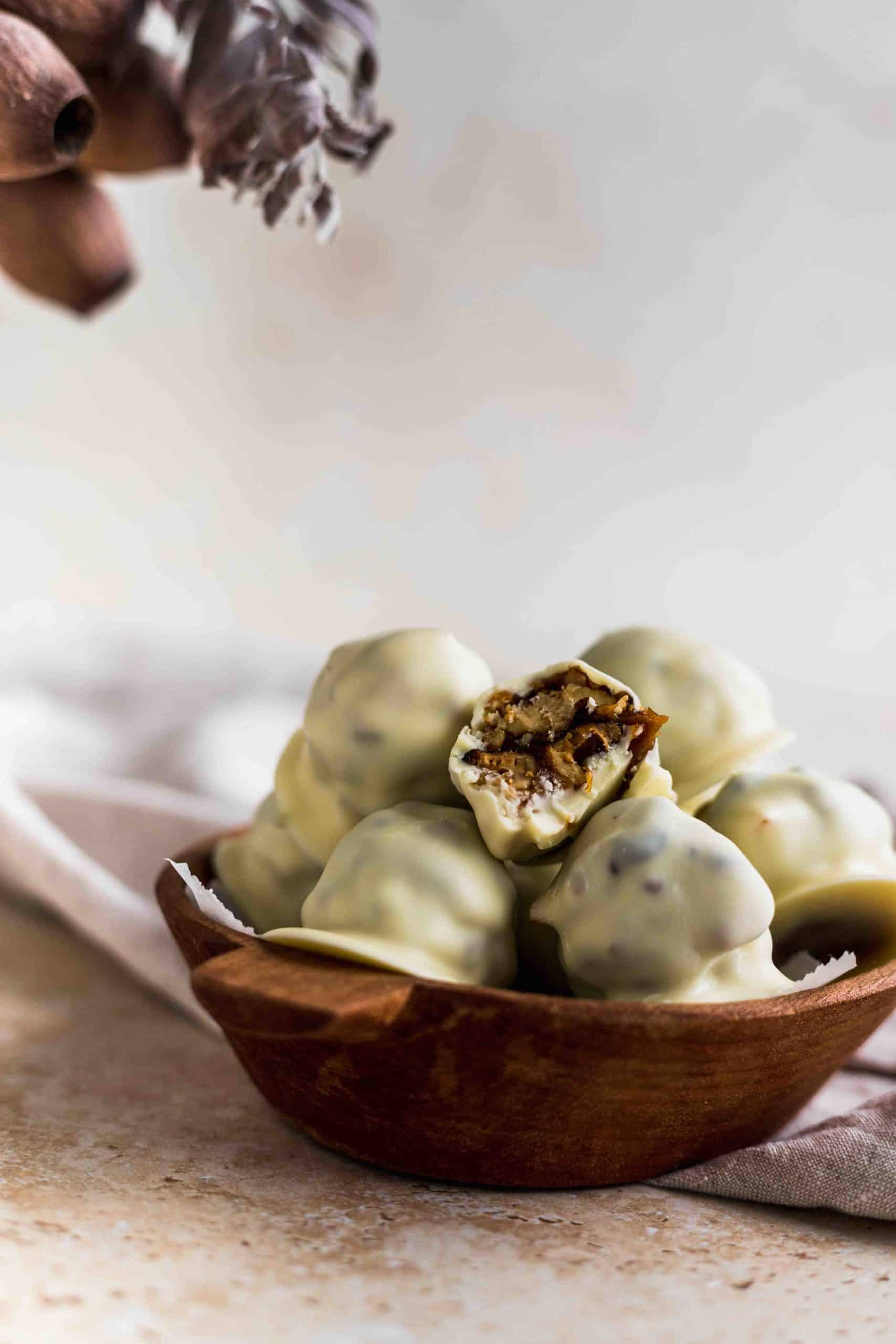 Close up of candied walnuts covered in white chocolate and filled with dule de leche on a wooden tray