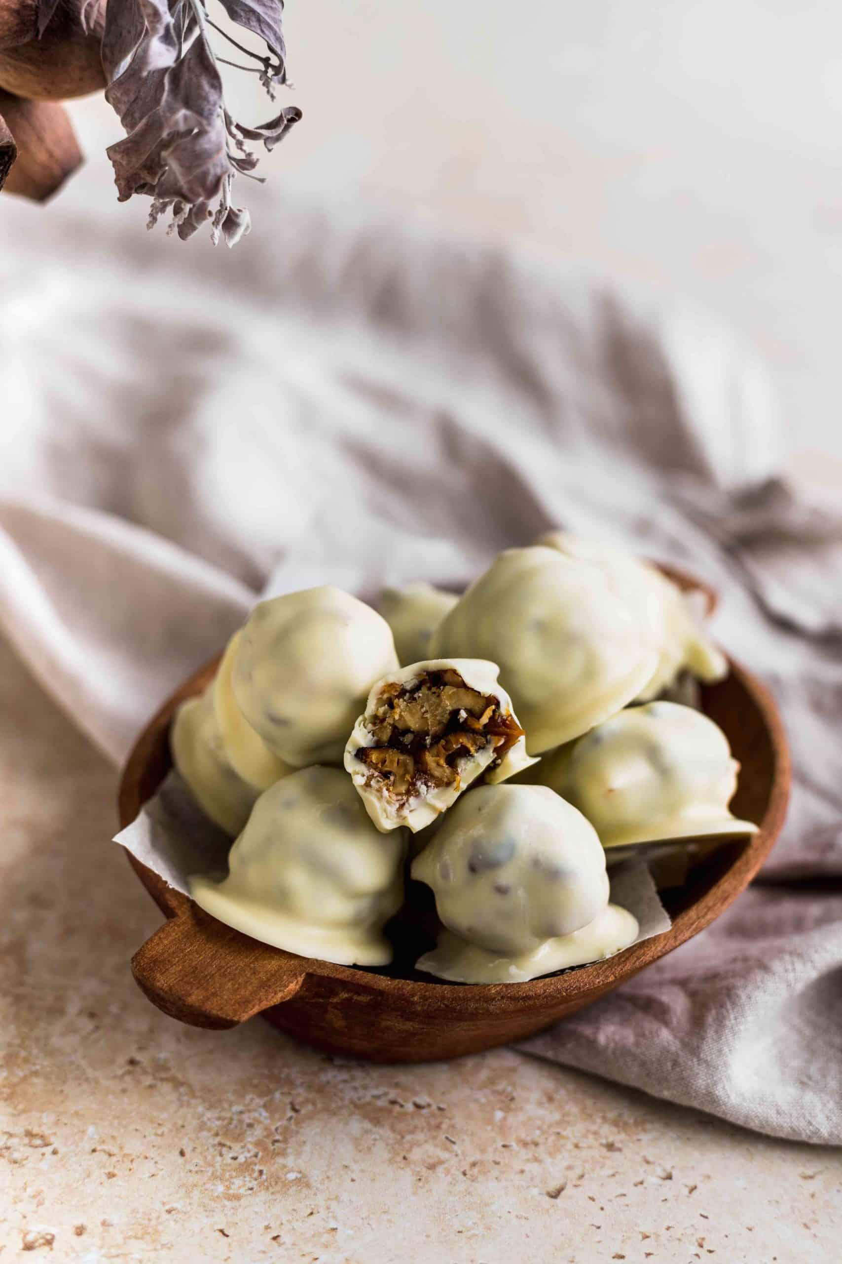 Nueces garrapiñadas cubiertas de chocolate blanco y rellenas con dulce de leche en una bandeja de madera