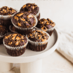 Chocolate muffins on a white cake stand and a white tea towel at the back - Pinterest
